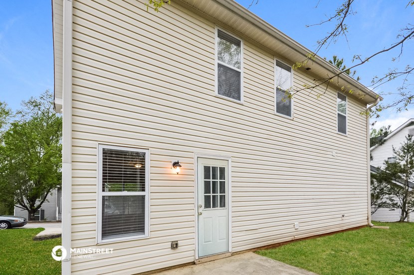 the front of a white house with a blue door