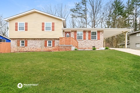 a yellow house with red shutters and a green lawn