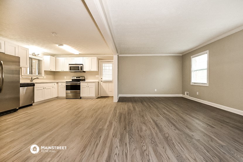 the living room and kitchen of an apartment with wood flooring