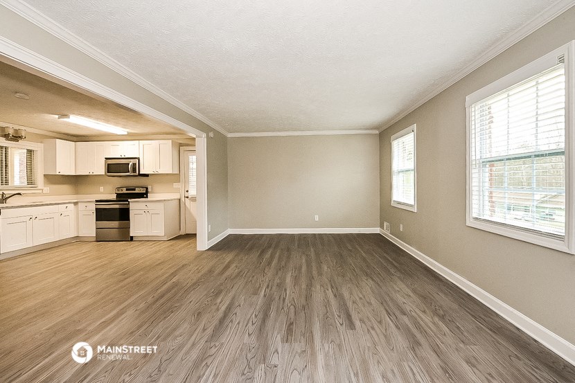 an empty living room and kitchen with wood flooring