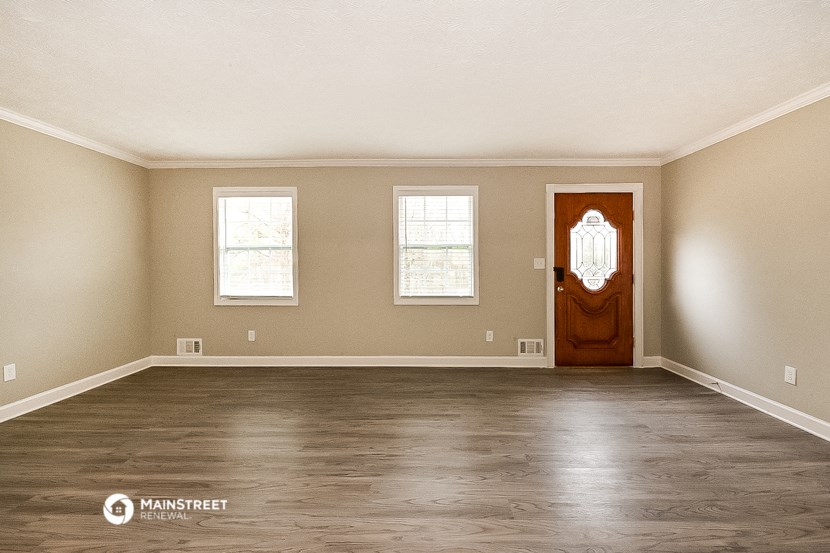 an empty living room with wood floors and a wooden door