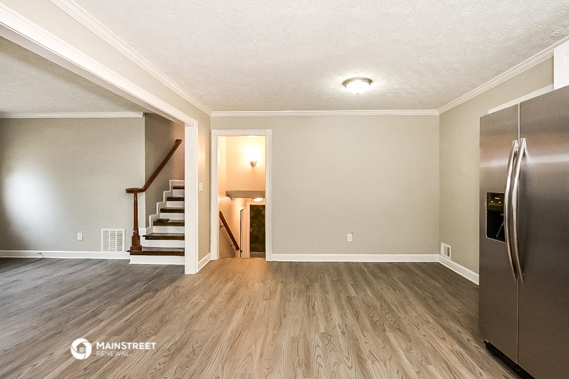 the living room of a house with a refrigerator and stairs