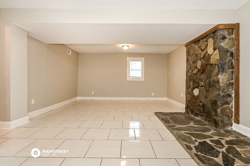 the spacious living room with a stone wall and tiled floor