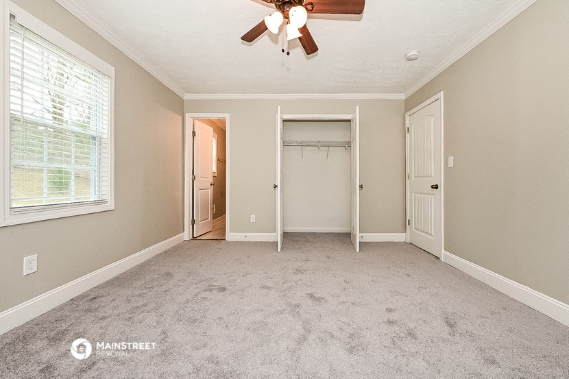 an empty bedroom with a ceiling fan and a closet
