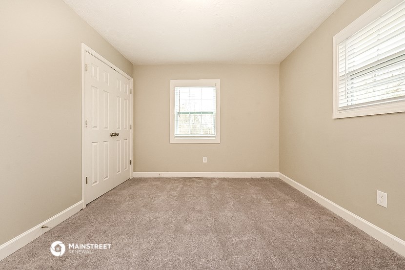 the spacious bedroom with carpeted flooring and a door to the bathroom