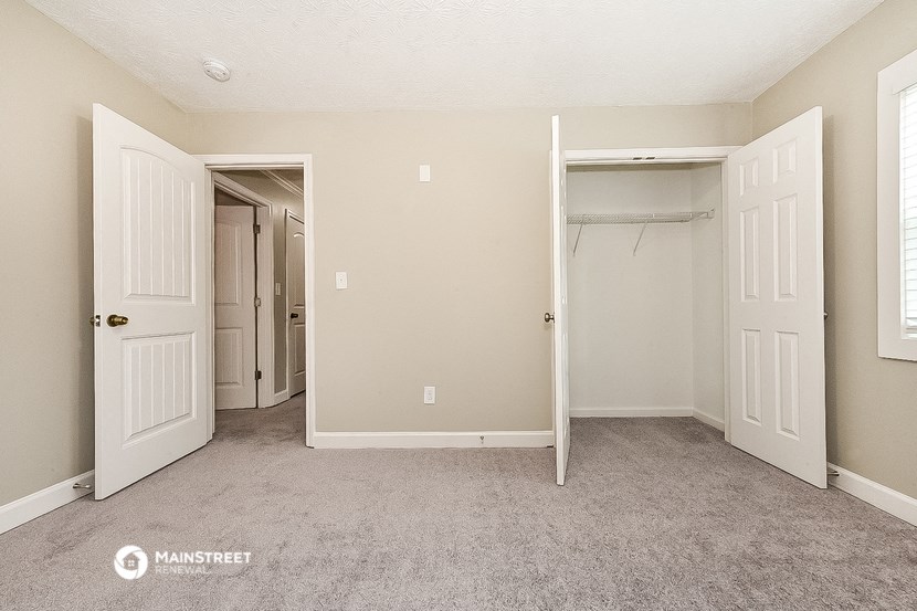 an empty bedroom with a closet and a mirrored closet door