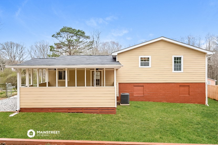 the front of a yellow house with a porch and a green lawn