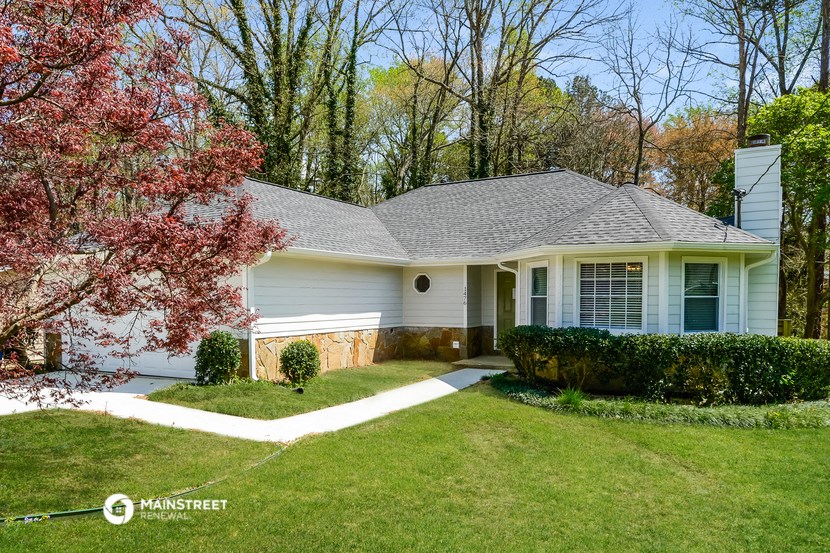 a white house with a lawn and a tree
