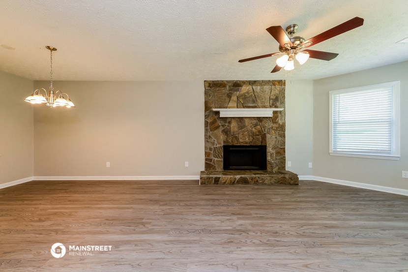 the living room with a fireplace and a ceiling fan