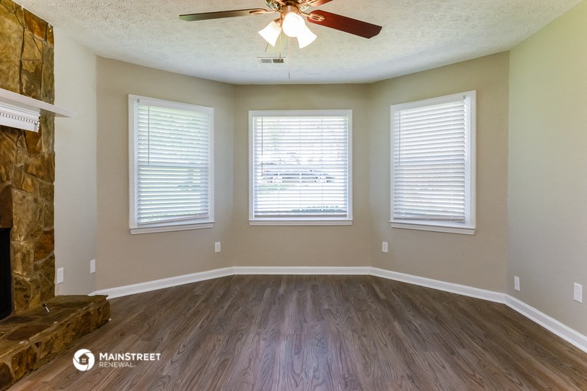 an empty living room with wood floors and a ceiling fan