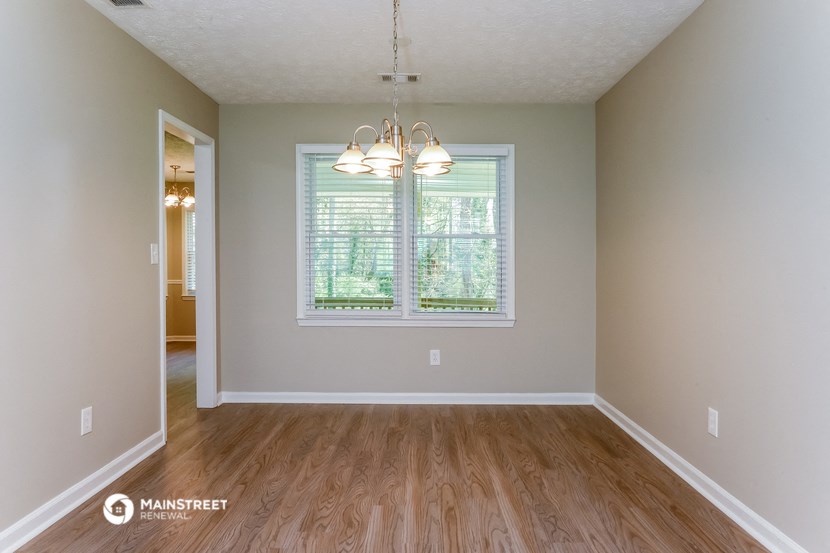 the spacious living room with hardwood flooring and a large window