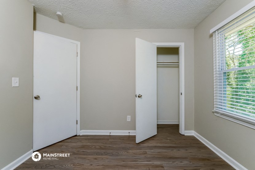 a bedroom with a door to a closet and a window