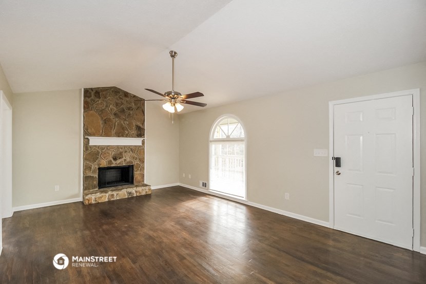 an empty living room with a fireplace and a ceiling fan