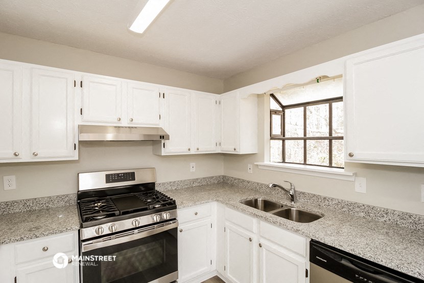 a kitchen with white cabinets and granite counter tops