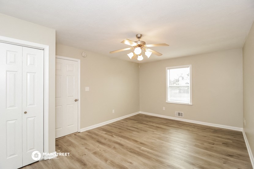 an empty living room with a ceiling fan and a door