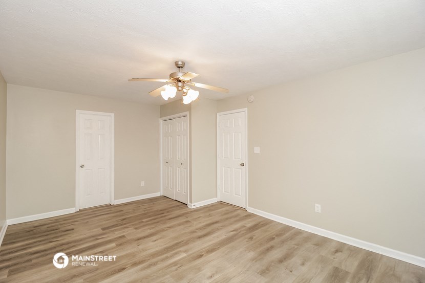 the spacious living room of this manufactured home has wood flooring and a ceiling fan