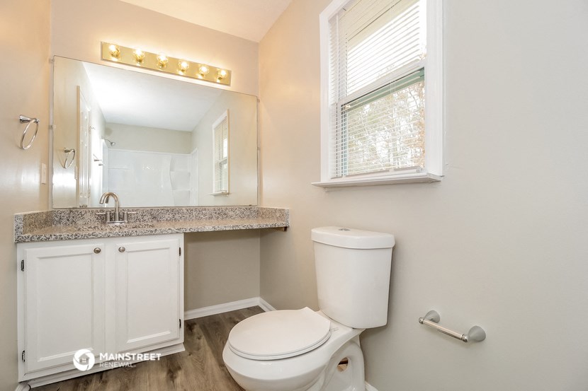 a bathroom with a toilet and a sink and a window