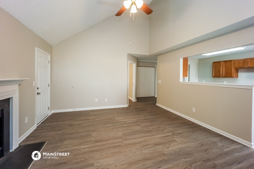 an empty living room with a fireplace and a ceiling fan