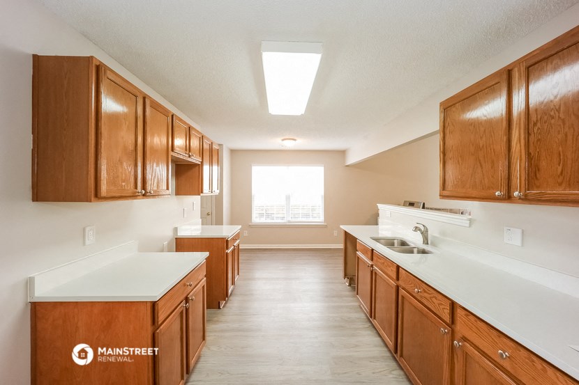 a kitchen with wooden cabinets and white counter tops and a window