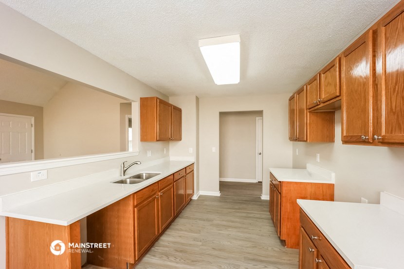 a kitchen with wooden cabinets and white counter tops and a sink