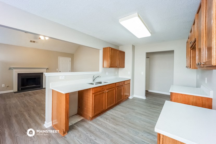 a kitchen with wooden cabinets and white countertops and a fireplace