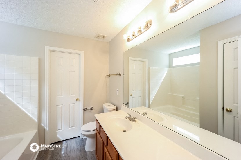 a bathroom with a large mirror and a sink and a toilet