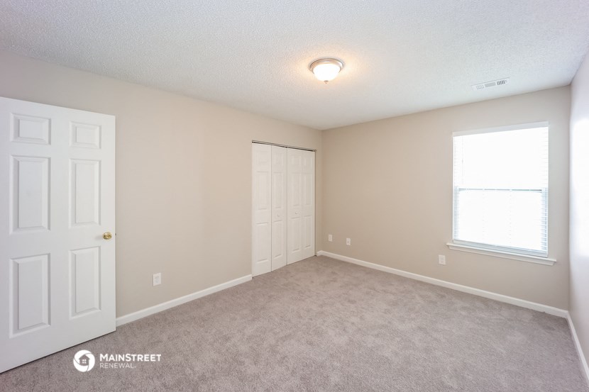 the spacious living room with a door to the closet and a window