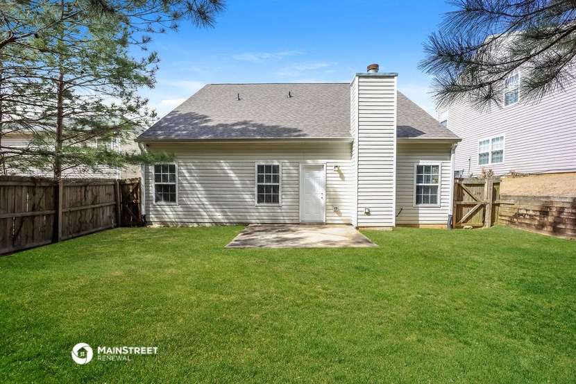 the back of a white house with a yard and a fence