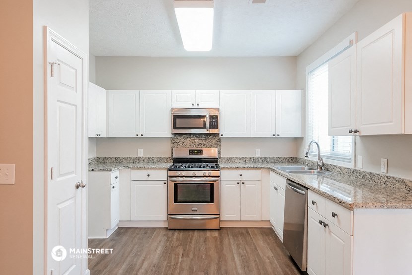a kitchen with white cabinets and granite counter tops and stainless steel appliances