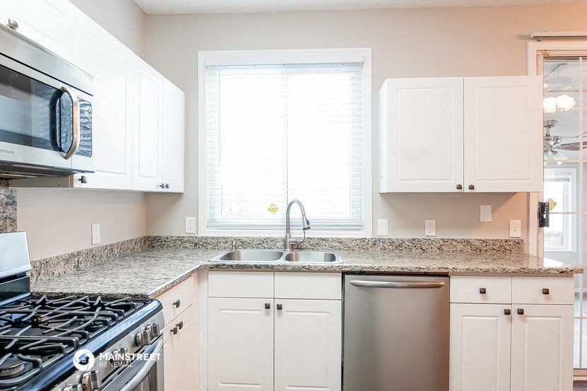 a kitchen with white cabinets and granite counter tops and a stainless steel sink