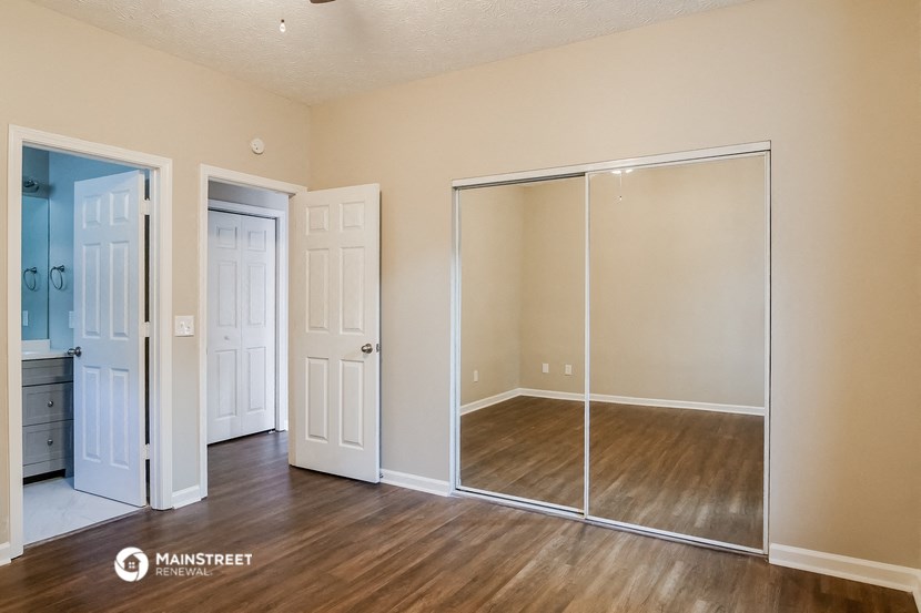a bedroom with mirrored closet doors and a hard wood floor