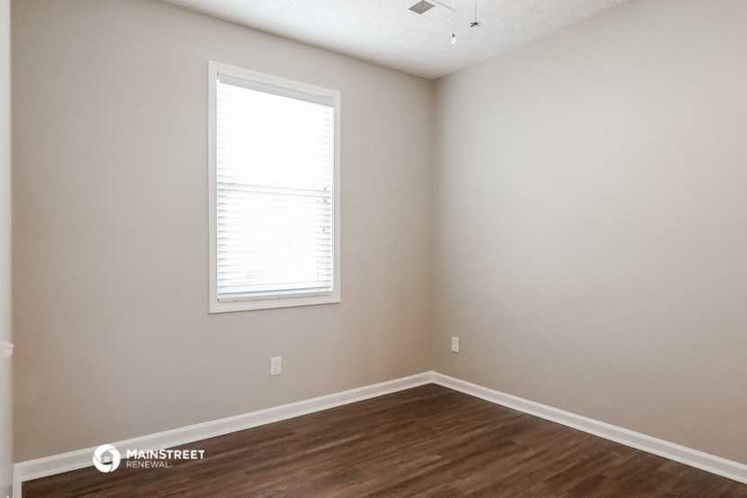 the interior of a bedroom with wooden floors and a window