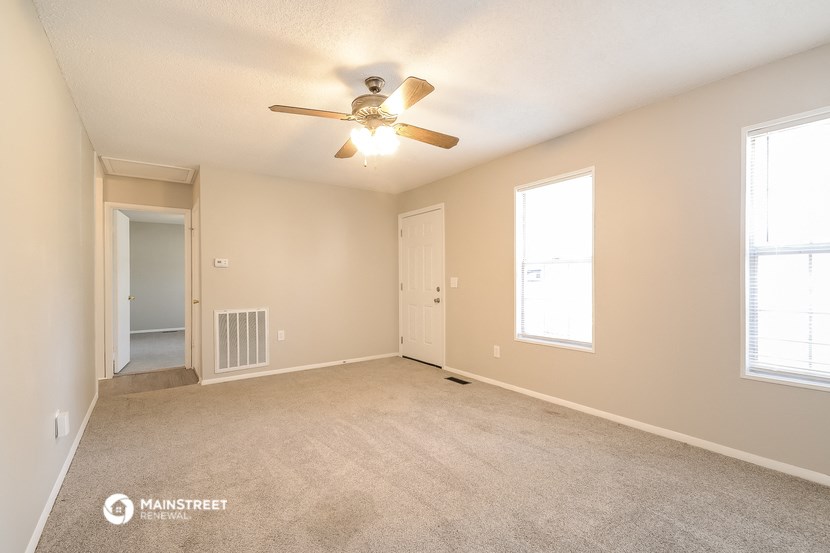 the spacious living room with carpet and ceiling fan