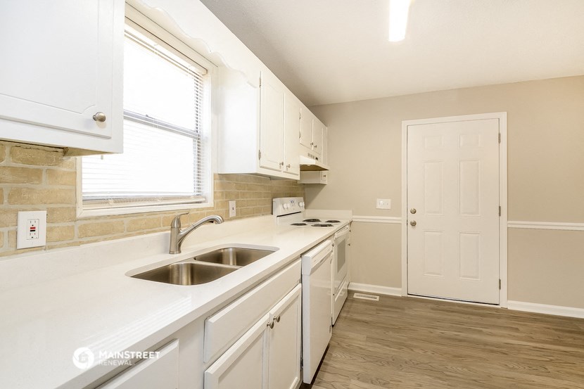 a kitchen with white cabinets and a sink and a window