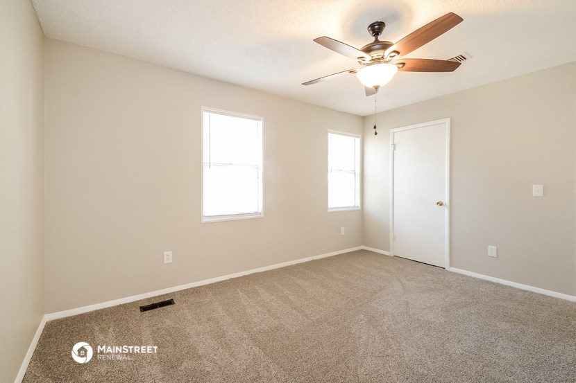 the spacious living room with carpet and ceiling fan