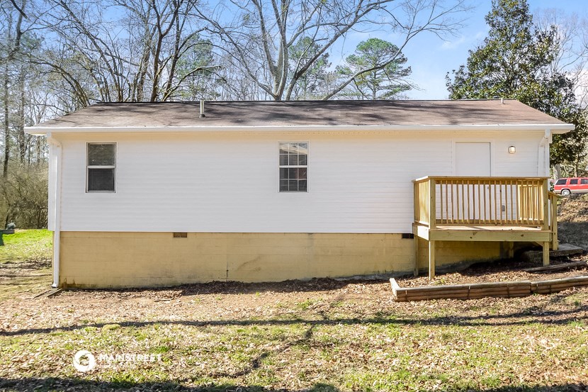 the front of a small white house with a wooden deck