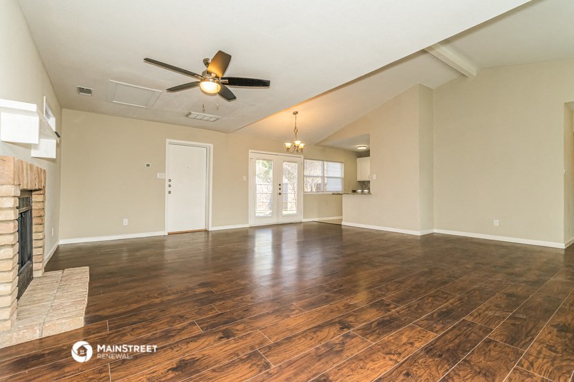 an empty living room with a fireplace and a ceiling fan