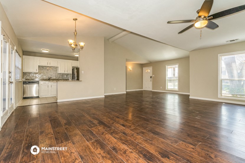 the living room and kitchen of an empty house with a ceiling fan