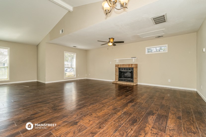 the living room with wood floors and a fireplace