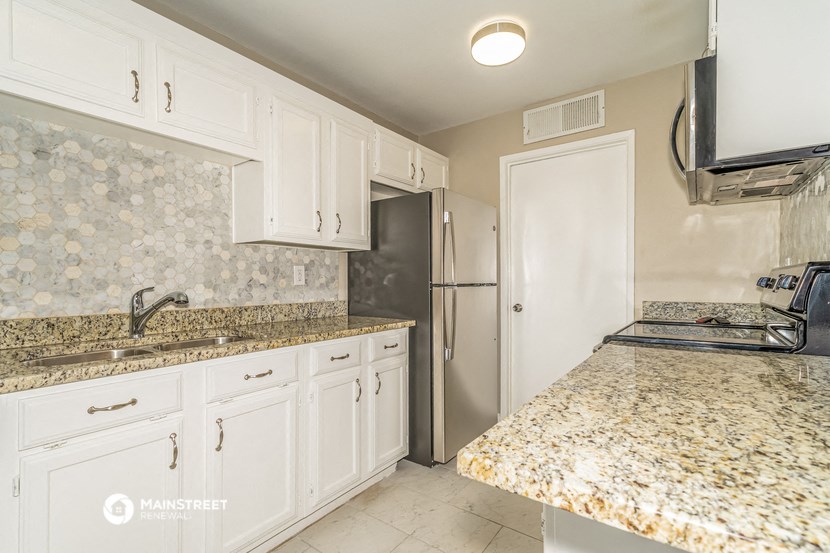 a kitchen with white cabinets and granite counter tops
