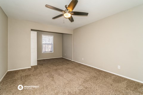 the spacious living room with ceiling fan and carpet