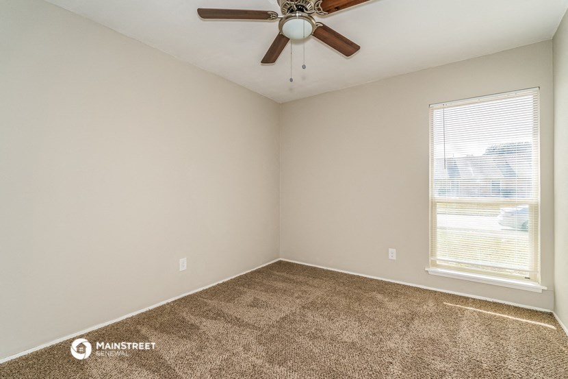 the spacious living room has carpet and a ceiling fan
