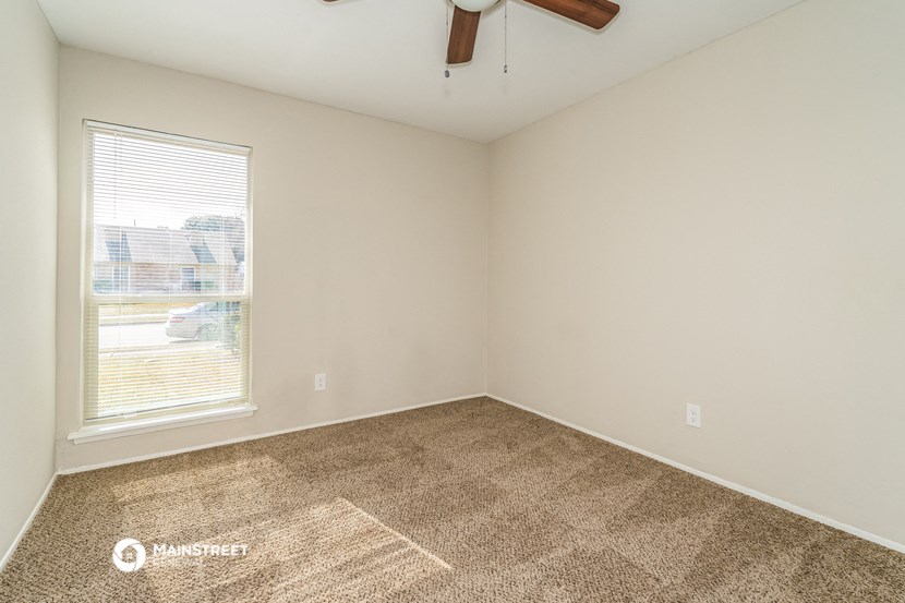 the living room of a home with a large window and carpeting