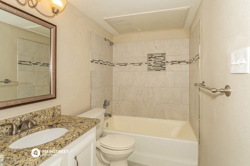 a bathroom with a tub toilet and sink and a mirror