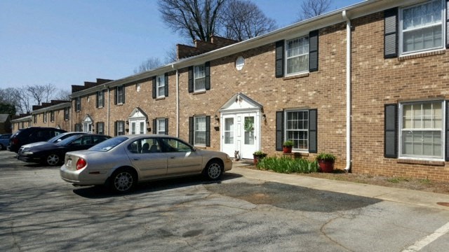 a car parked in a parking lot in front of a brick apartment building
