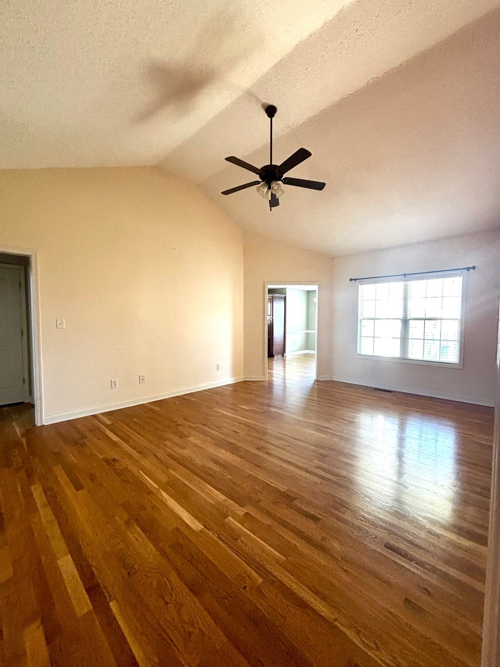 A room with a ceiling fan and wooden floors.