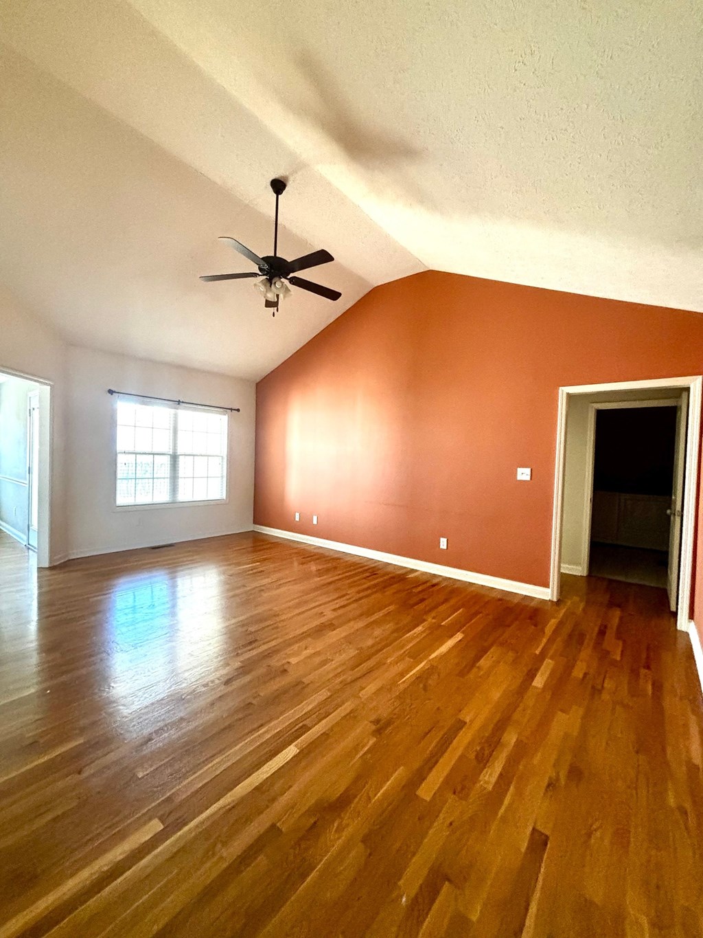 A room with a ceiling fan and wooden flooring.