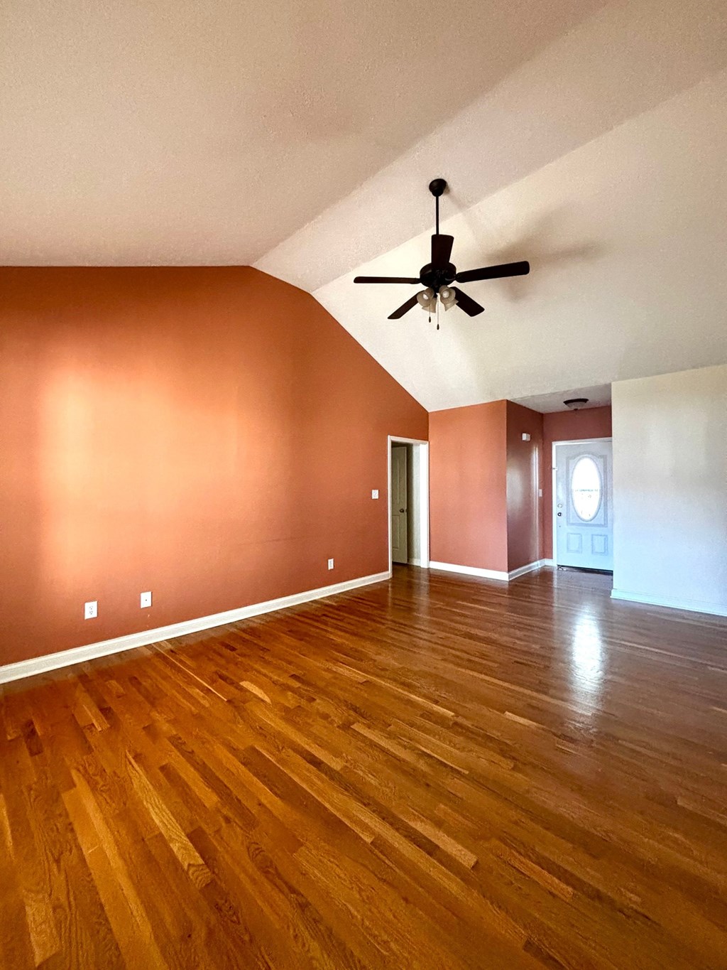 A room with a ceiling fan and wooden flooring.