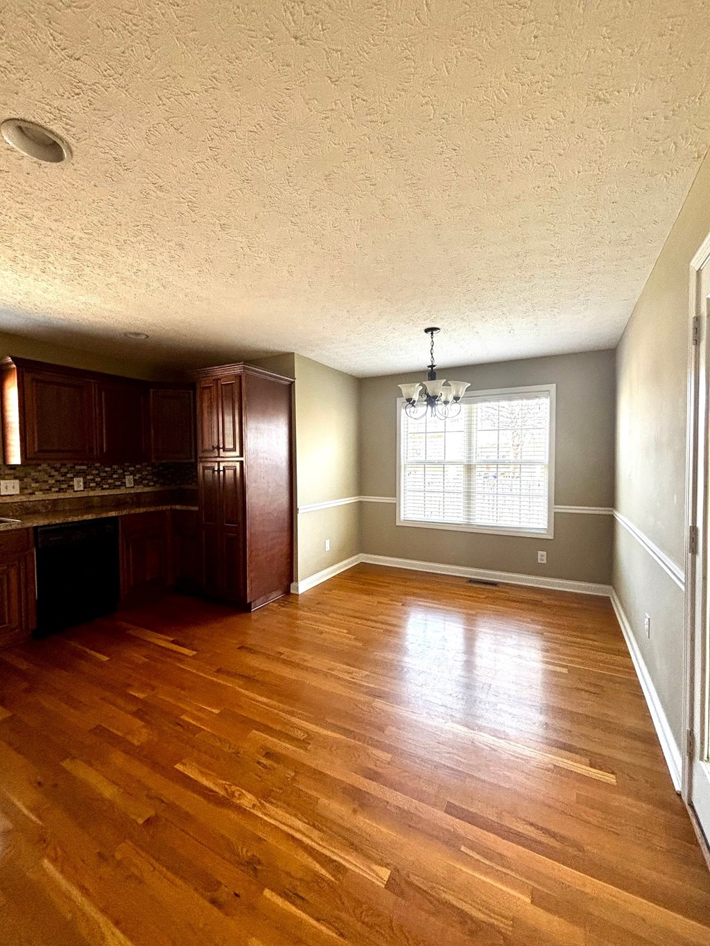 A room with wooden floors and a window with blinds.