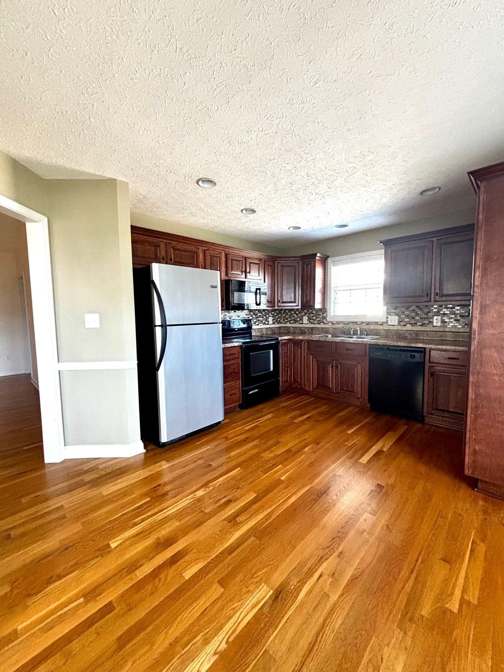 A kitchen with wooden floors and dark brown cabinets.